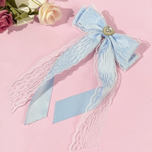 Détail de la pince à cheveux en dentelle bleu clair avec strass en cœur et rubans de satin