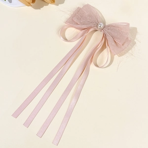 Detailed macro shot of pink bow hair clip with mesh wings, pearls and long satin ribbons