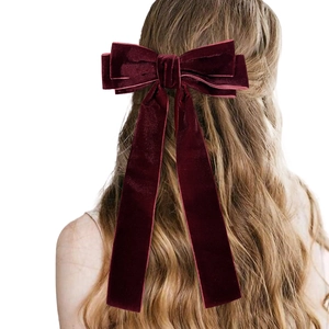 Detail view of burgundy velvet bow hair clip with long ribbons on a female hairstyle