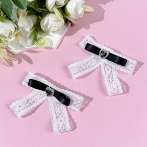 Close-up of lace bow hair clips with black heart rhinestone and satin ribbon details