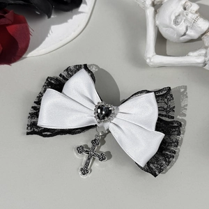 Détail de la pince à nœud gothique avec dentelle noire, gemme cœur et pendentif croix