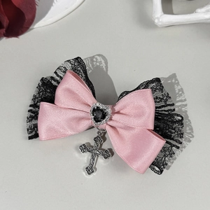 Détail de la barrette nœud en satin rose avec dentelle noire, gemme cœur et croix argentée