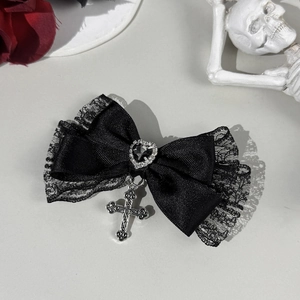 Détail d'un nœud en dentelle noire avec pierre en cœur et pendentif croix en argent vintage
