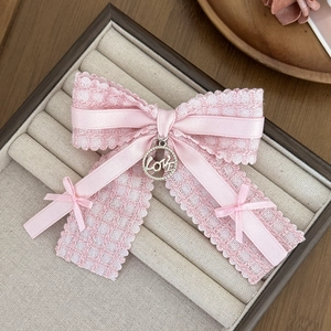 Detailed close-up of pink lace bow hair clip with silver LOVE charm in jewelry box