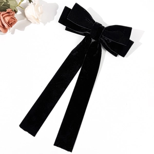 Elegant black velvet bow hair clip with long ribbons on a white background with roses