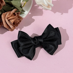 Détail d'un nœud papillon en satin noir multicouche avec un éclat soyeux sur fond rose