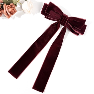 Detailed view of the luxury burgundy velvet fabric and vintage bow design on hair clip