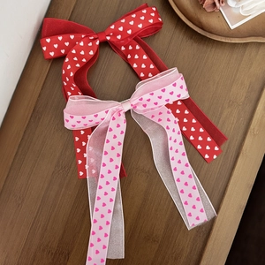 Noeuds à cheveux rouges et roses à motifs cœurs avec de longs rubans sur bois