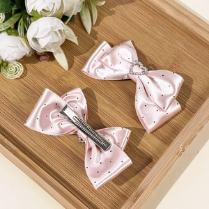 Detalle de horquillas de lazo rosa con lunares, diamantes de imitación de corazón y clip metálico