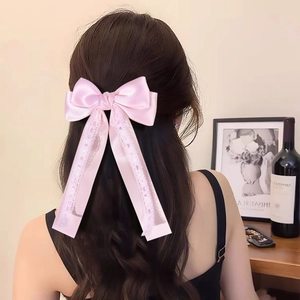 Pink satin bow hair clip with lace trim and long ribbons shown on long wavy hair