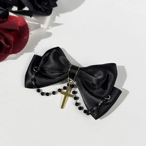 Close-up of black satin bow hair clip with golden cross pendant and dark gothic beads
