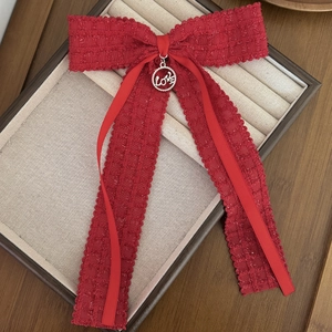 Detailed macro view of a red tweed bow hair clip featuring a silver metal LOVE pendant