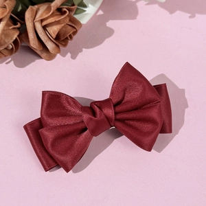 Gros plan sur la barrette à nœud en satin bordeaux élégante avec texture soyeuse et couches