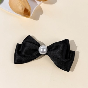 Détail de la pince à cheveux nœud noir avec perle centrale et tissu texturé