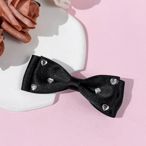Close-up of black satin bow hair clip with sparkling heart-shaped rhinestones