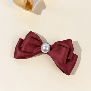Vue détaillée d'une pince à cheveux nœud satin bordeaux avec une perle blanche centrale
