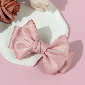 Gros plan détaillé d'une pince à cheveux nœud en satin rose avec texture de ruban