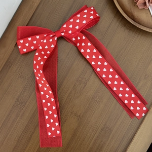 Vue détaillée du nœud papillon rouge avec motif à cœurs sur un fond en bois sombre
