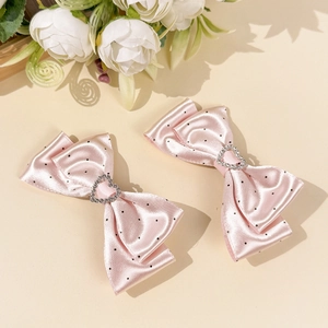 Detalle de horquillas de satén rosa con lunares y corazón de strass para el pelo