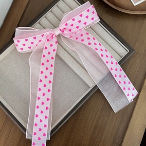 Barrette à cheveux rose avec nœud en tulle à motifs de cœurs sur un plateau à bijoux