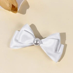 Détail de la pince à cheveux nœud en satin blanc ornée d'une perle centrale élégante