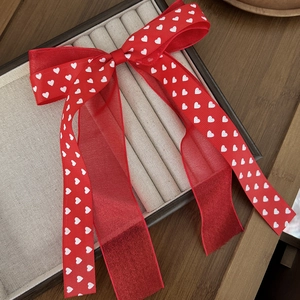 Détail d'un nœud papillon rouge à motifs cœurs en ruban et mousseline sur écrin