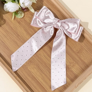 Fermaglio per capelli in raso rosa a pois con lunghi nastri su vassoio in legno
