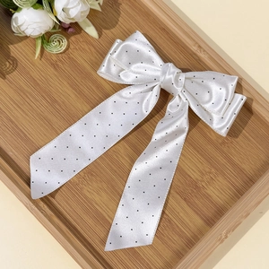 Dettaglio del fermaglio a fiocco in raso bianco a pois con lunghi nastri eleganti