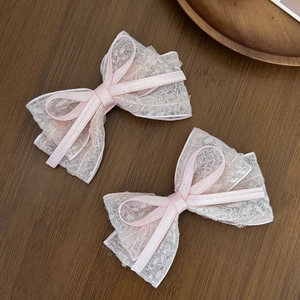 Macro detail of sweet pink lace bow hair clips with floral texture and satin ribbons