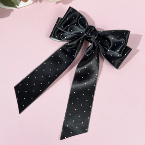 Dettaglio del fiocco in raso nero a pois con lunghi nastri fluenti per capelli