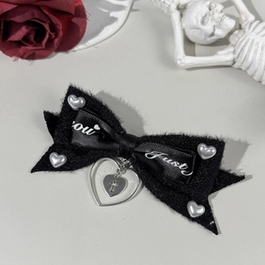 Detail of gothic black plush hair bow with heart charms and a cross pendant detail
