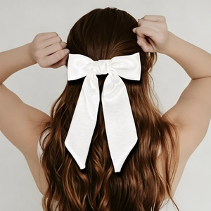 Detail of white satin long tail bow hair clip with silky texture on long wavy hair
