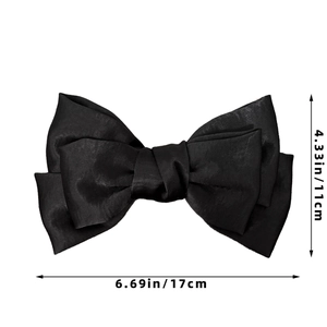 Detail view of large black satin bow hair clip showing fabric texture and 17cm dimensions