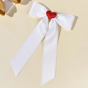 Detail of white satin bow hair clip with red heart and serrated scalloped lace edges