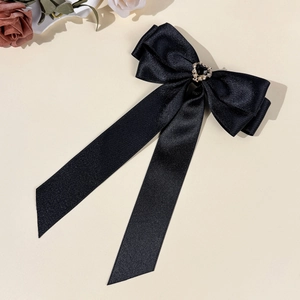 Macro view of black satin bow hair clip with vintage heart jewel and gold metal frame
