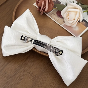 Elegant white satin bow hair clip with luxury pearl sheen and metallic spring barrette