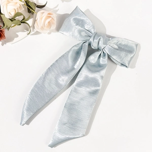 Detail of light blue satin bow hair clip with elegant long ribbons on a white background