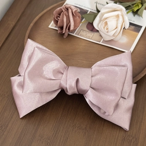 Detail of pink satin bow hair clip on a vintage wooden tray with elegant dried flowers
