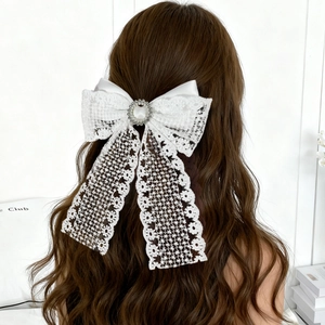 Détail d'un nœud à cheveux en dentelle blanche avec grande perle et accents de strass