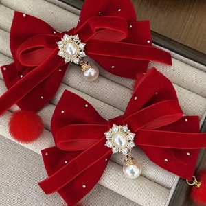 Lazos de terciopelo rojo con perlas y pedrería en un joyero de color beige claro