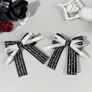 Detail of gothic black and white ribbon hair bows with elegant cursive letter printing