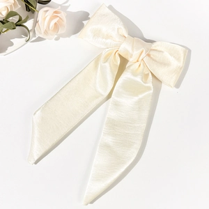 Detailed macro view of the cream satin bow hair clip showing smooth texture and elegant ribbon