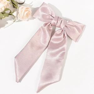 Detail of elegant pale pink satin bow hair clip with long flowing ribbons for women