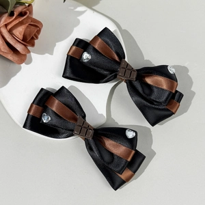 Dettaglio di fermagli Lolita al cioccolato con nastri neri e marroni e strass a cuore