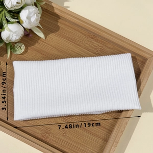 White ribbed knitted sports headband for workout shown on bamboo tray with floral accents