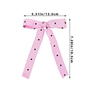 Pink and white striped bow hair clip with black heart patterns and long streamers