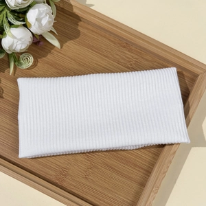 Detail of white ribbed knit headband with elastic texture on natural wood tray