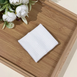 Detail view of a white knitted sports wristband on a natural wooden bamboo tray with flowers