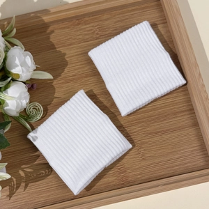 Close-up of white ribbed sports wristbands pair on a wooden tray with floral accents