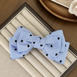 Barrette à cheveux avec nœud rayé bleu et blanc et motifs cœurs noirs sur plateau